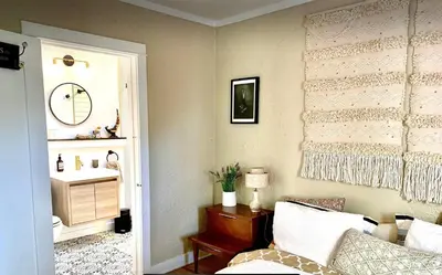 a living room with a bed and a sink at Romantic cottage with amazing garden in Glendale