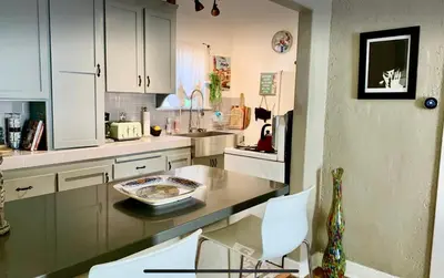a kitchen with white cabinets and a table and chairs at Romantic cottage with amazing garden in Glendale