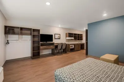 a bedroom with a bed and a desk with a television at WoodSpring Suites Bellflower - Los Angeles in Bellflower