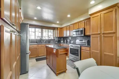 a kitchen with wooden cabinets and stainless steel appliances at Luxury Oasis Home w/Pool Near CSUN-6 Guests in North Hills