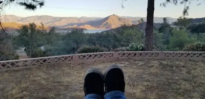 a person with their feet up on a bridge at Panoramic Lake View, Lake Isabella in Wofford Heights