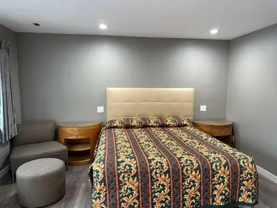 a bedroom with a bed and a chair at Stay Inn Motel in Harbor City