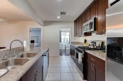 a kitchen with stainless steel appliances and wooden cabinets at 5 Bedroom Charmer with Pool in Reseda