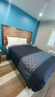 a bedroom with a bed with a blue wall at Plaza Inn Motel - Los Angeles area in Rosemead
