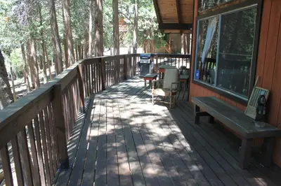 a porch of a cabin with a bench and trees at Cozy Sequoia Forest Cabin near Lake Isabella in Wofford Heights