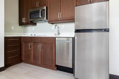 a kitchen with a stainless steel refrigerator and wooden cabinets at Residence Inn by Marriott Anaheim Brea in Brea