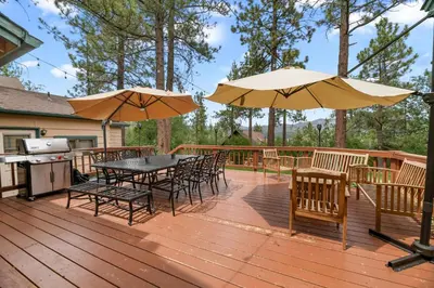 a deck with tables and chairs and umbrellas at Narrow Escape - Close to Lake and Slopes in Big Bear Lake