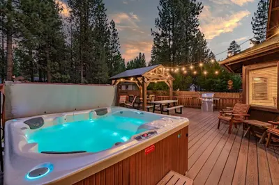 a hot tub on a deck with a table and chairs at A Snowmass Haven - EV, Sauna, Hot Tub - Walk to Slopes/lake in Big Bear Lake
