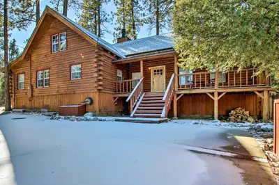 a log cabin with a porch in the snow at Pine Mountain Club Log Home with Deck and Grill! in Pine Mountain Club