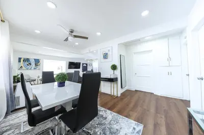 a dining room with a white table and black chairs at Luxury Villa with Hot Tub! Minutes to Beach & Bars in Long Beach