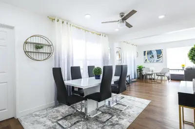 a dining room with a white table and black chairs at Luxury Villa with Hot Tub! Minutes to Beach & Bars in Long Beach