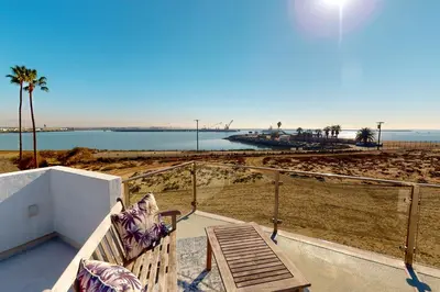 a bench on a balcony looking at the beach at Gull Cottage in Seal Beach