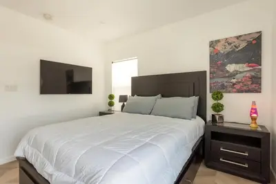 a white bedroom with a large bed and a television at Coziest 1BD Bungalow 8min from airport, 4 min SoFi in Los Angeles