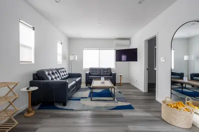 a living room with a black leather couch and a table at Bungalow w Free Parking 4 min from SoFi, 8min from airport in Los Angeles