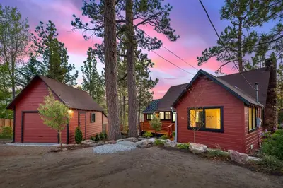 a small red house with a garage in the woods at Sled-Ski Snow Summit Lakeside Village - Spa - BBQ - Firepit - Loft - Games in Big Bear Lake