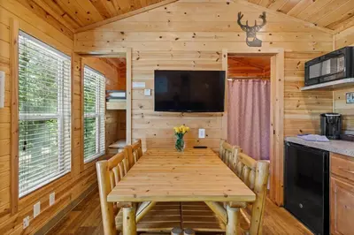 a dining room with a wooden table and a tv at Quiet little pet friendly cabin in Kernville