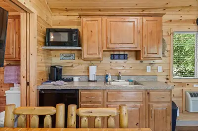 a kitchen with wooden cabinets and a sink and a microwave at Adorable little cabin #26 in Kernville