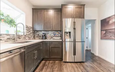 a kitchen with wooden cabinets and a stainless steel refrigerator at Gorgeous DTLA w/ View + Hot Tub! in Los Angeles