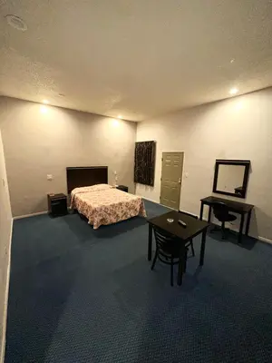a bedroom with a bed and a table and a desk at Tropic West Motel in Bell