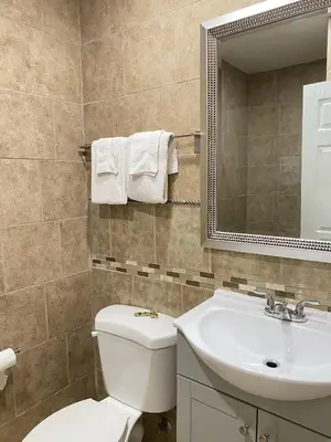a bathroom with a toilet and a sink and a mirror at City Center Motel - Oxnard in Oxnard