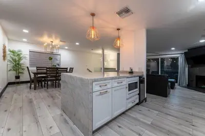 a kitchen with a counter and a dining room with a table at Modern San Pedro Home, Sleeps 12, Hot Tub, Fire Place, Private Parking in San Pedro