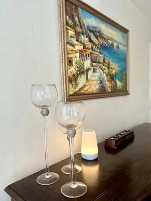 two wine glasses sitting on a table with a painting at Elegant Hollywood Retreat - Spacious 2BR 2BA Condo with Resort-Style Amenities in Los Angeles