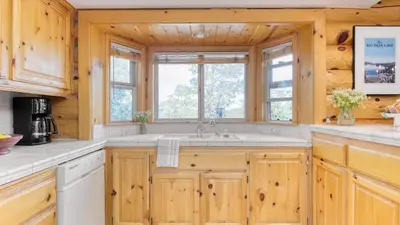 a kitchen with wooden cabinets and a sink at Tanglewood by AvantStay 10mins to Bear Mountain Contemporary Hillside Cabin in Big Bear Lake