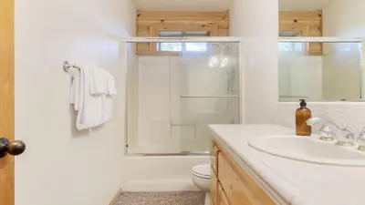 a white bathroom with a shower and a sink at Tanglewood by AvantStay 10mins to Bear Mountain Contemporary Hillside Cabin in Big Bear Lake