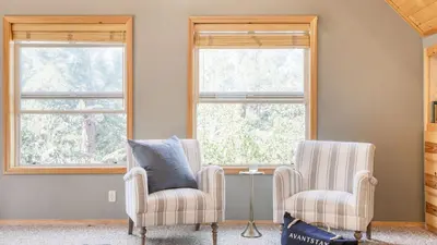 two chairs in a living room with two windows at Tanglewood by AvantStay 10mins to Bear Mountain Contemporary Hillside Cabin in Big Bear Lake