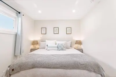 a white bedroom with a large bed with two lamps at Gameroom Sofi Stadium Forum Backyard BBQ in Hawthorne