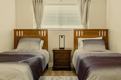 a bedroom with two beds and a window and a night stand at Cozy Family Home - 20 Mins from Disneyland in Placentia