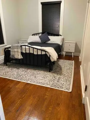 a bedroom with a bed and a rug on a wooden floor at Downtown 3 bed newly renovated with amenities. in Bakersfield