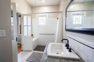 a white bathroom with a sink and a shower at Downtown 3 bed newly renovated with amenities. in Bakersfield