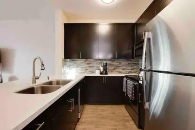 a kitchen with black cabinets and a stainless steel refrigerator at The Nest a Spacious 1 Bedroom Apartment with a Pool View in Los Angeles