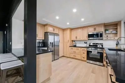 a kitchen with wooden cabinets and black appliances at Updated Mountain Cabin Retreat with 180 views off Deck and Balcony in Running Springs