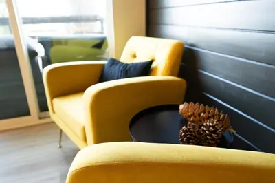 a living room with a yellow chair and a pine cone at Updated Mountain Cabin Retreat with 180 views off Deck and Balcony in Running Springs