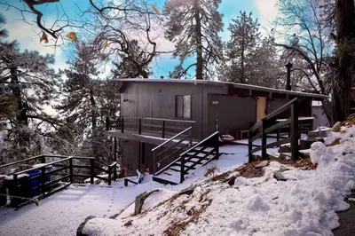 a small cabin in the woods in the snow at Updated Mountain Cabin Retreat with 180 views off Deck and Balcony in Running Springs