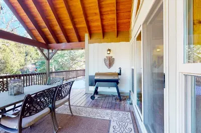a porch with a table and chairs and a grill at Arrowhead Haven in Lake Arrowhead