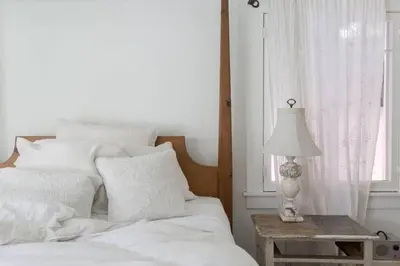 a white bed with a table with a lamp on it at Elegant White Cottage, Venice Beach, California in Los Angeles