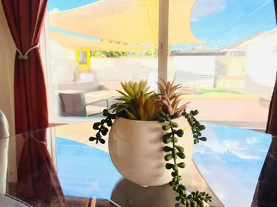 a vase with a plant sitting on a glass table at Garden Suite - 10 mins to Beach and LAX in Gardena