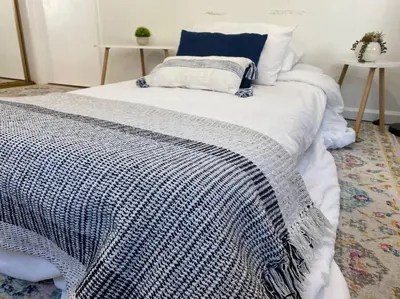 a bed with a blue and white blanket on it at Garden Suite - 10 mins to Beach and LAX in Gardena
