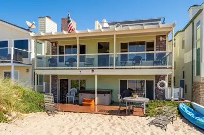 a house on the beach with a table and chairs at Beautiful Ocean Front Coastal Sunset Beach House in Oxnard