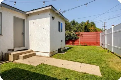 a yard with a white house and a fence at The Heart Of LA House in Los Angeles
