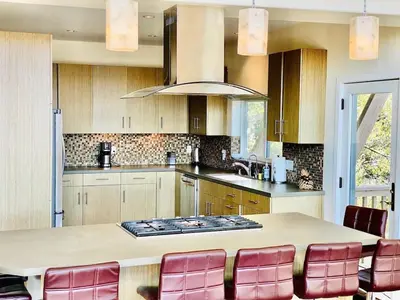 a kitchen with a large table with red chairs at Modern 6 bedroom retreat, stunning lake views, close to village! in Lake Arrowhead