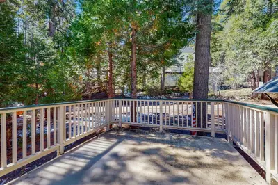 a white fence on a porch with trees at Vintage Village Walk Cottage in Lake Arrowhead