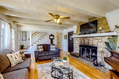 a living room with a fireplace and a ceiling fan at Vintage Village Walk Cottage in Lake Arrowhead
