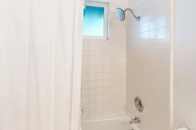 a bathroom with a tub and a shower with a window at Saint Bernard Beauty in Lake Arrowhead