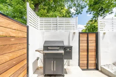 a grill in a backyard with a wooden fence at New luxury entertaining house with Pool Spa Sauna Tesla charger Pets in Los Angeles