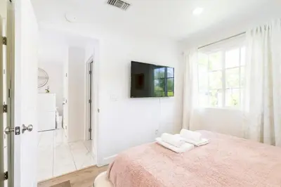 a white bedroom with a bed and a tv on the wall at New luxury entertaining house with Pool Spa Sauna Tesla charger Pets in Los Angeles