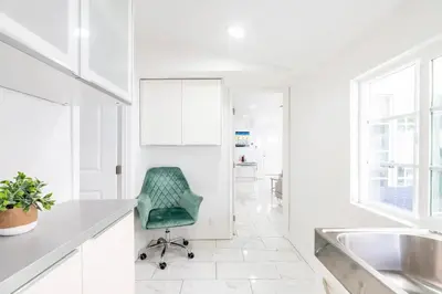 a kitchen with a green chair in a white room at New luxury entertaining house with Pool Spa Sauna Tesla charger Pets in Los Angeles